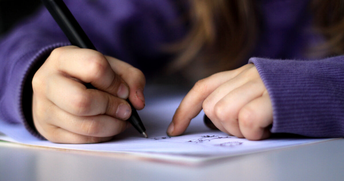 Niño practicando dibujo y escritura con lápiz sobre papel